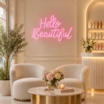 Krem koltuklu güzellik salonunun açık renk duvarında pembe Hello Beautiful LED neon yazısı