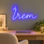 Adaçayı grisi çalışma odasında ahşap masa üzerinde mavi İrem LED neon yazısı