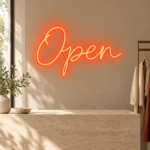 Butik girişinde açık renk duvarda kırmızı el yazısı Open LED neon tabela