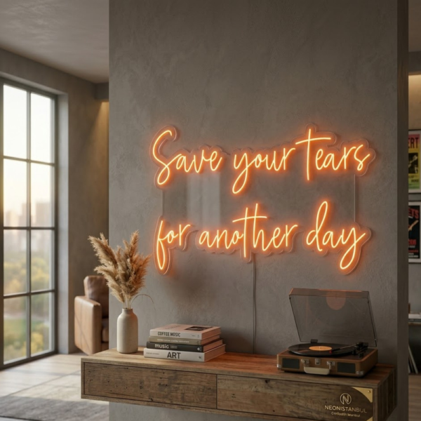 Gri duvarda ahşap konsolun üzerinde, sıcak turuncu ışıkla Save your tears for another day yazılı LED neon tabela